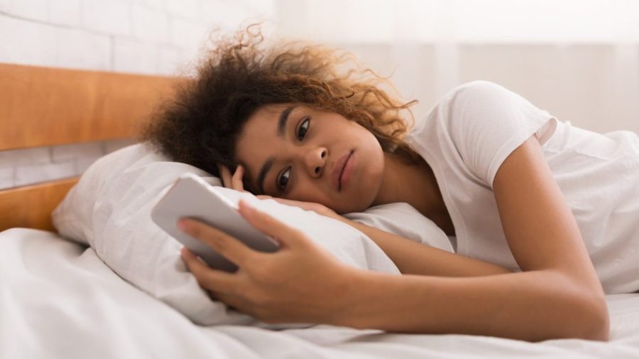 Image: a young woman looks worriedly at her phone