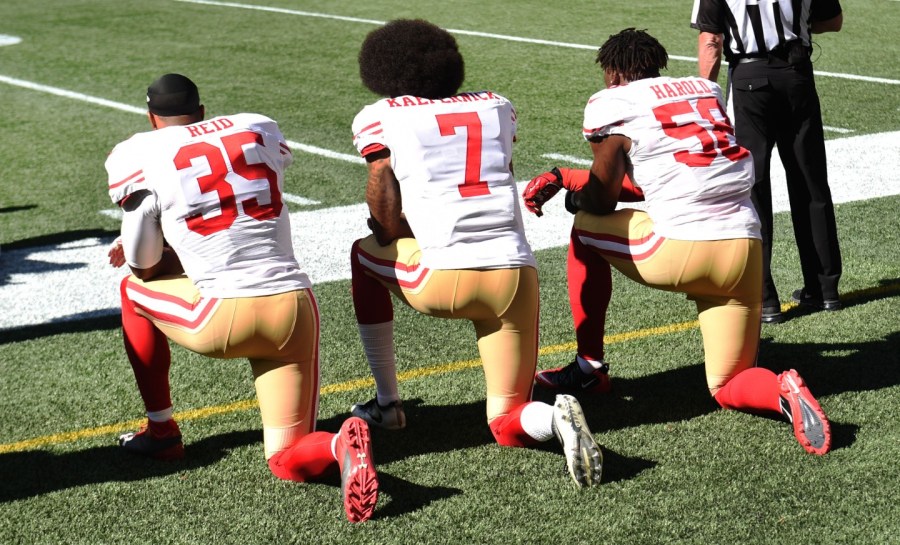 Colin Kaepernick and other football players kneel during the National Anthem