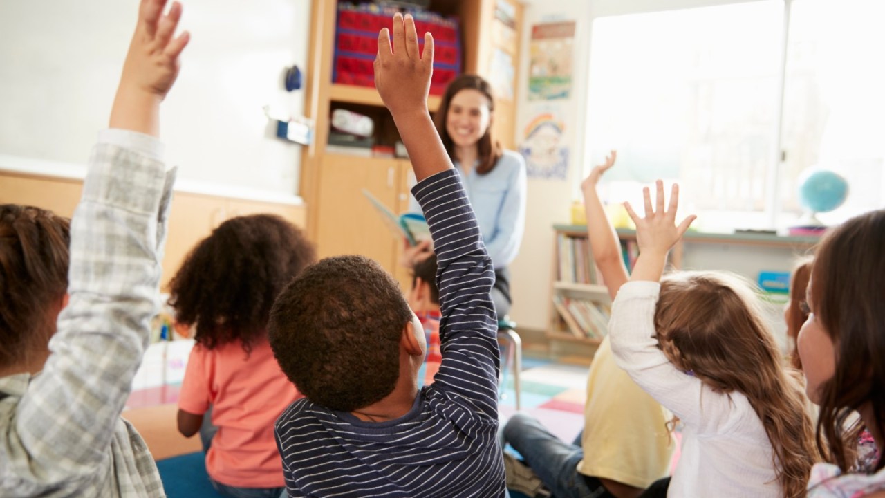 Children raise their hands in a classroom