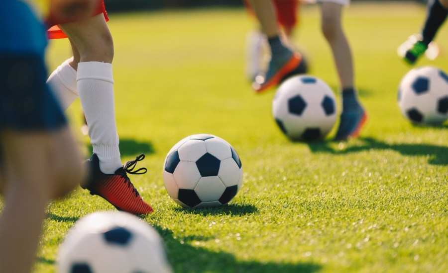 People's feet kick around a soccer ball