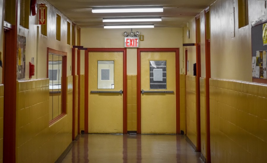 an empty school hallway showing an exit sign