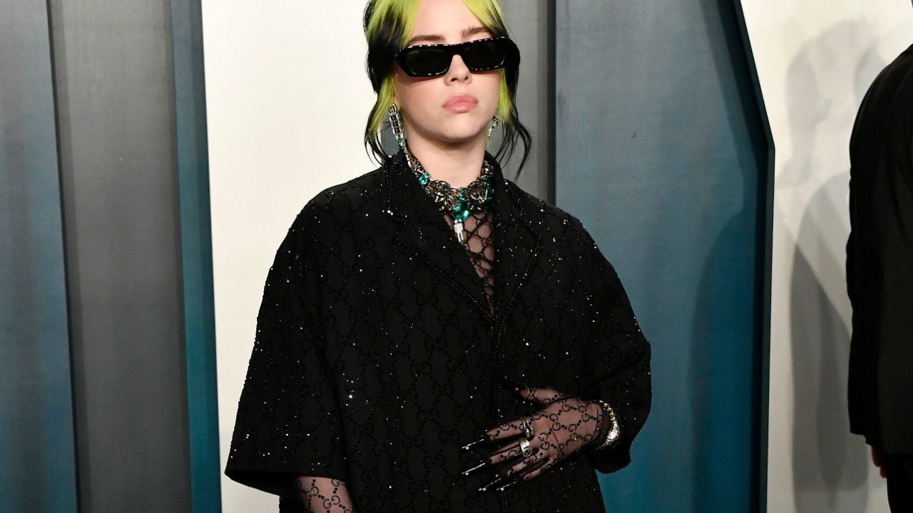 billie eilish on the red carpet for an afterparty wearing a loose black top with sheer black gucci sleeves underneath