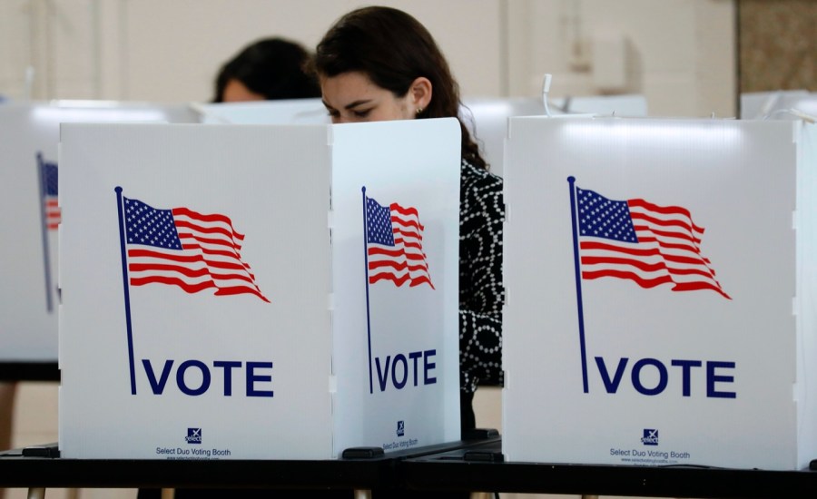 a voter behind the screen of a voting booth