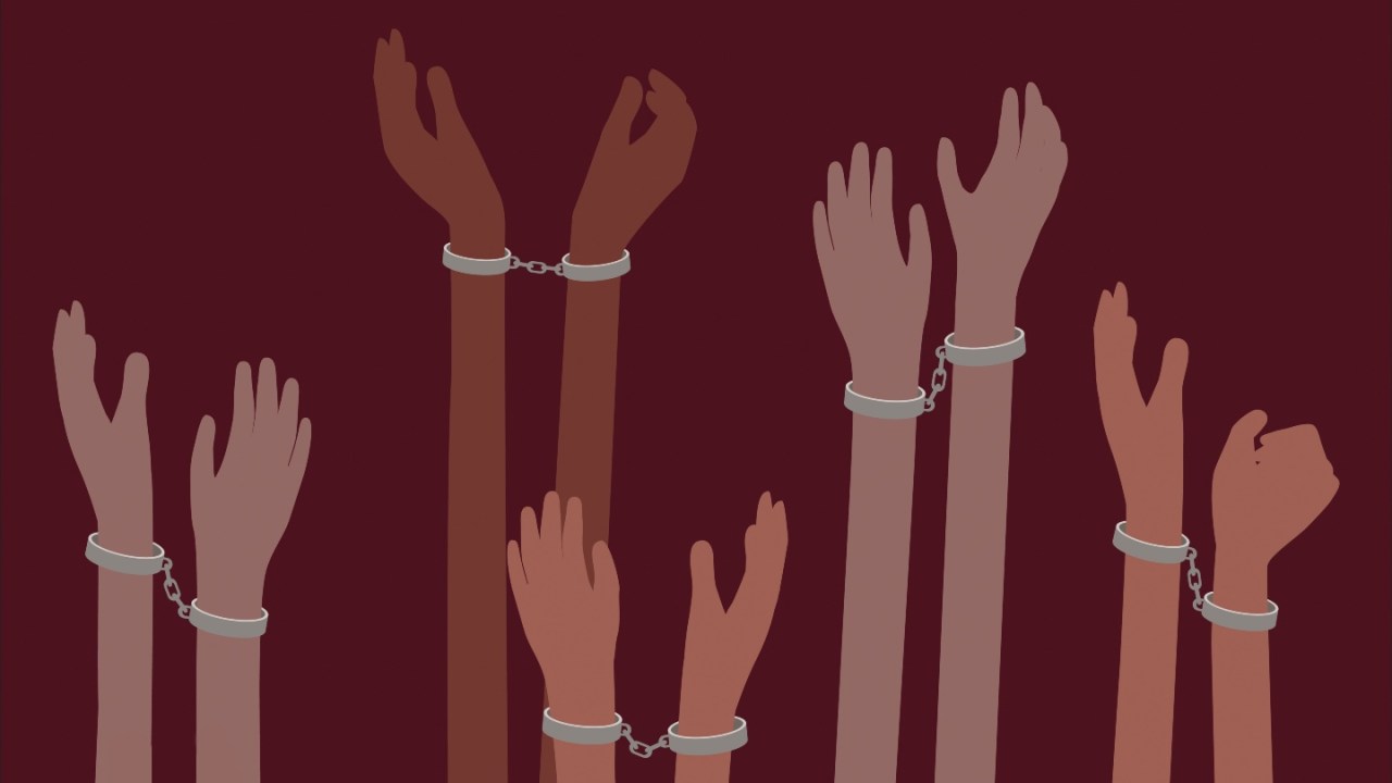 an illustration of hands of different colors in shackles held up against a maroon background