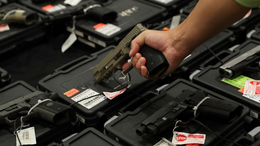 A potential buyer tries out a gun which is displayed on an exhibitor's table during the Nation's Gun Show