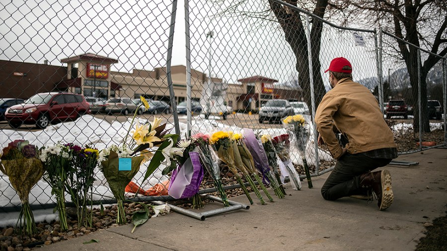 A mourner leaves flowers and pays tribute the morning after a gunman opened fire at a King Sooper's grocery store on March 23, 2021 in Boulder, Colorado.