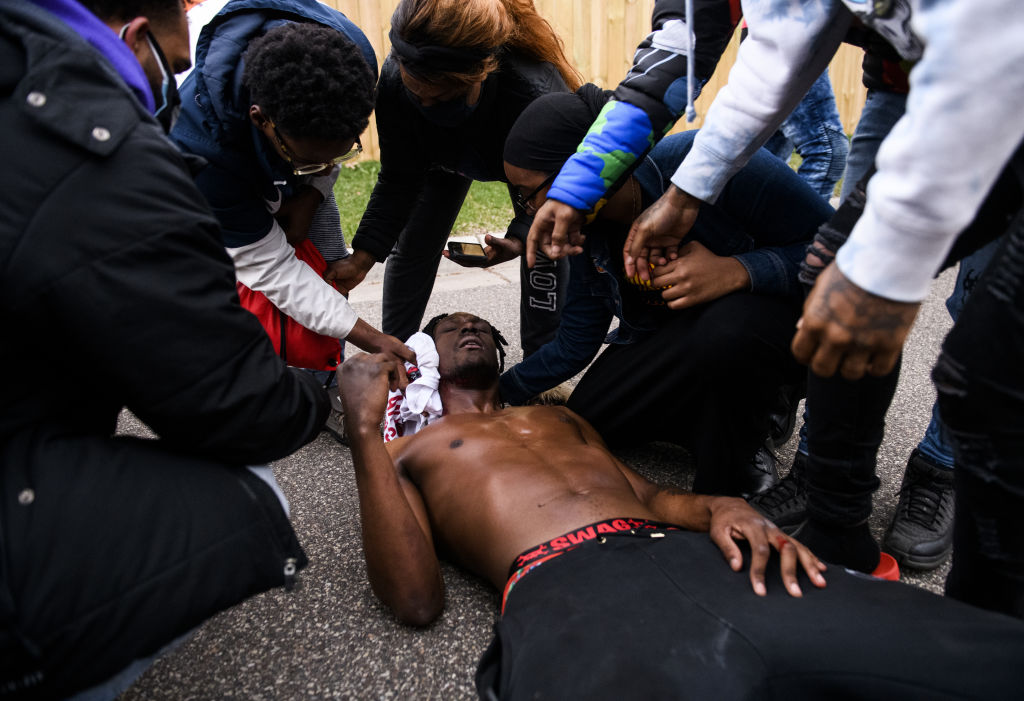 People treat a man who was shot in the neck with a projectile by police on April 11, 2021 in Brooklyn Center, Minnesota. Protesters took to the streets today after 20 year old Daunte Wright was shot and killed during a traffic stop by members of the Brook