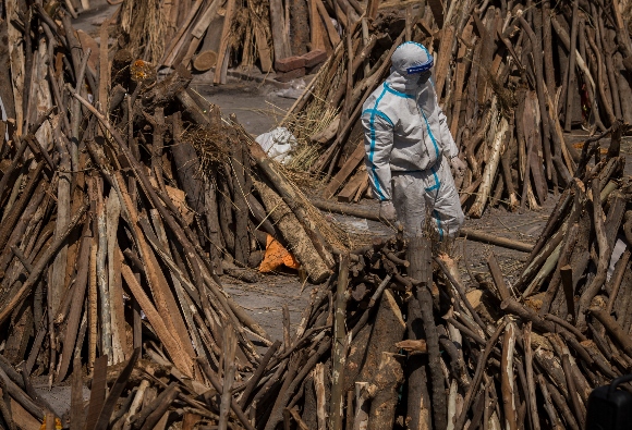 A man wearing PPE kit can be seen amid funeral pyres before they were lit 