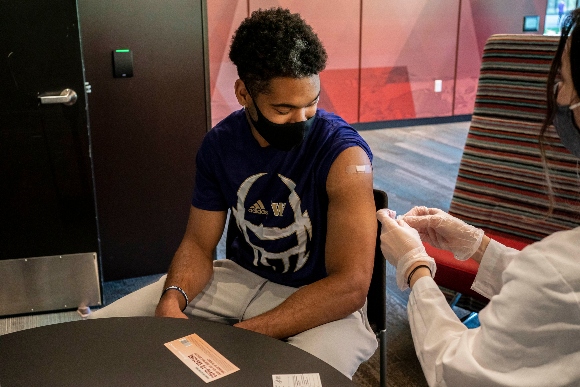 Julius Irvin, a student athlete on the football team, receives a COVID-19 vaccine at a vaccination clinic on the University of Washington campus 