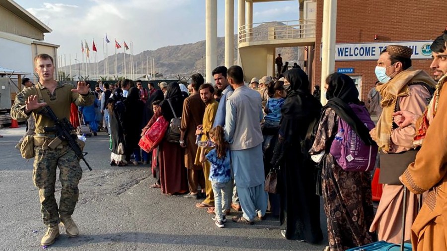 Afghan people queue up to board a U.S. military aircraft to leave Afghanistan from the Kabul airport