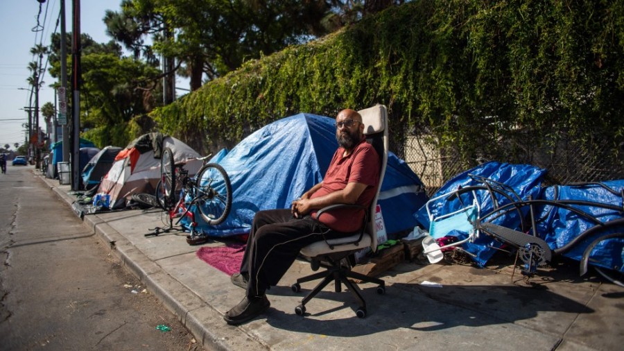 Albert Martinez, who has lived for 20 years on the streets of Los Angeles, sits outside his tent on a sidewalk in Venice Beach