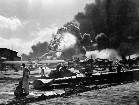 Sailors stand amid wreckage watching as the USS Shaw explodes December 7, 1941 on Ford Island, Pearl Harbor, Hawaii