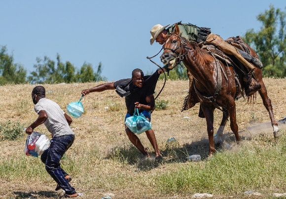 A United States Border Patrol agent on horseback tries to stop a Haitian migrant