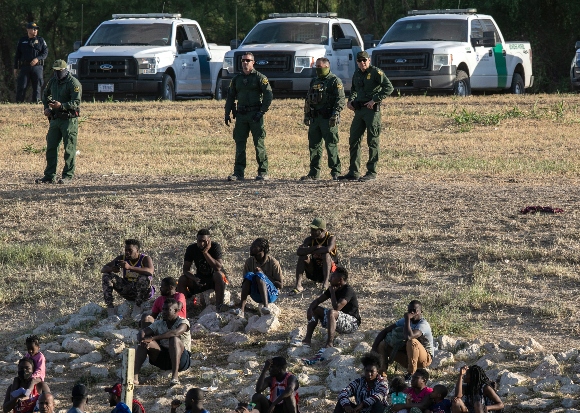 U.S. Border Patrol agents watch over immigrants near a migrant camp in Del Rio, Texas