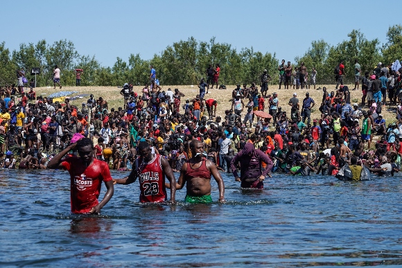 Haitian migrants, part of a group of over 10,000 people staying in an encampment on the US side of the border, cross the Rio Grande river