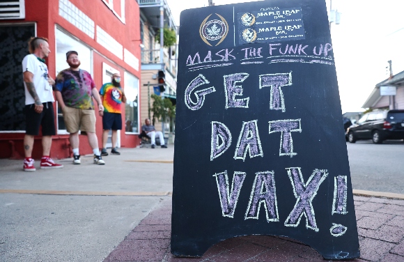 A sign reads 'Get Dat Vax!' in front of a popup vaccination clinic