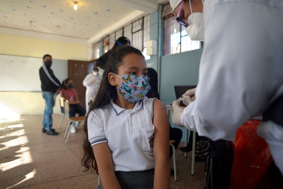 A health worker inoculates a child against COVID-19 with a dose of the CoronaVac vaccine