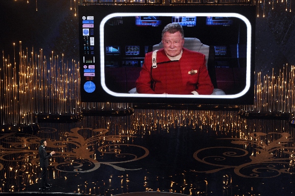 Host Seth MacFarlane talks to actor William Shatner on the video screen during the Oscars