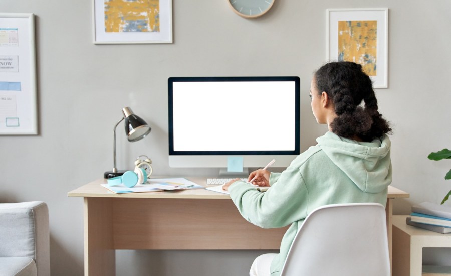 young teen sitting at a desk looking at a computer screen