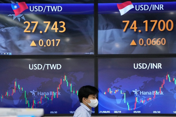 A currency trader walks near screens showing the foreign exchange rates