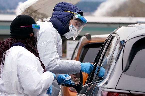 COVID-19 testing specialists Alex Honn, right, and Tokeya Berry test a driver at a drive-up coronavirus testing location