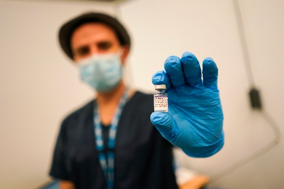 A member of staff holds up a vial of a coronavirus vaccine