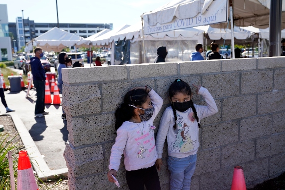 Two girls wait in line at a COVID-19 testing site on the Martin Luther King Jr. medical campus