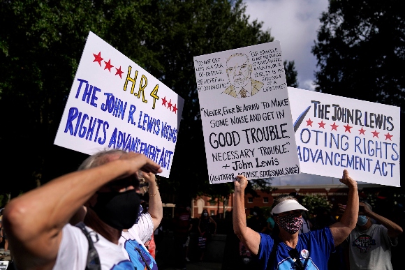 Demonstrators holds a sign during a march for voting rights, marking the 58th anniversary of the March on Washington