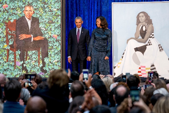 Former President Barack Obama and former first lady Michelle Obama stand on stage together as their official portraits are unveiled