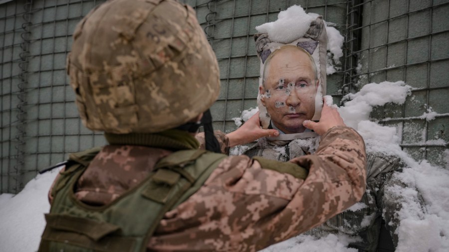 A Ukrainian serviceman shakes snow off a bullet riddled effigy of Russian President Vladimir Putin in the Luhansk region of Eastern Ukraine