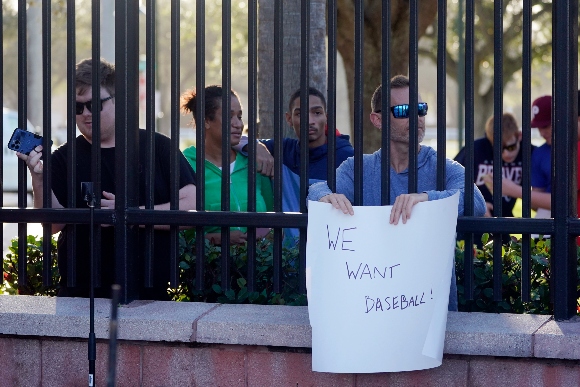 Baseball fans watch as Major League Baseball Commissioner Rob Manfred speaks during a news conference