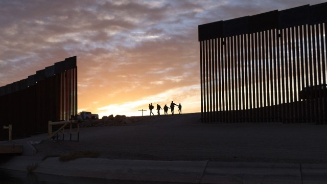 Migrant families from Brazil pass through a gap in the border wall to reach the United States