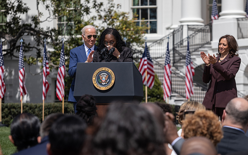 Justice Ketanji Brown Jackson addresses supporters at the presidential podium with President Biden and Vice President Harris in the background