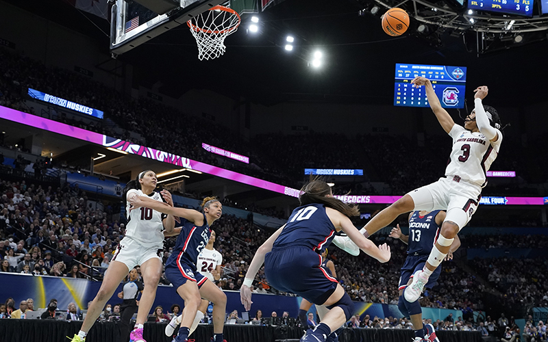 Destanni Henderson shoots a basketball into the air as other players attempt to block