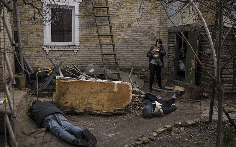 Ira Gavriluk holds her cat as she walks next to the bodies of her husband, brother and another man on the ground