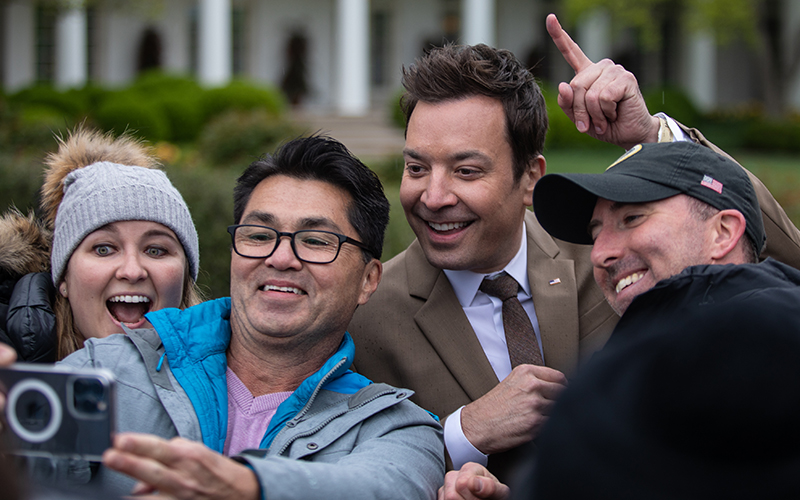 Comedian and talk show host Jimmy Fallon, right from center, stops for a selfie with fans