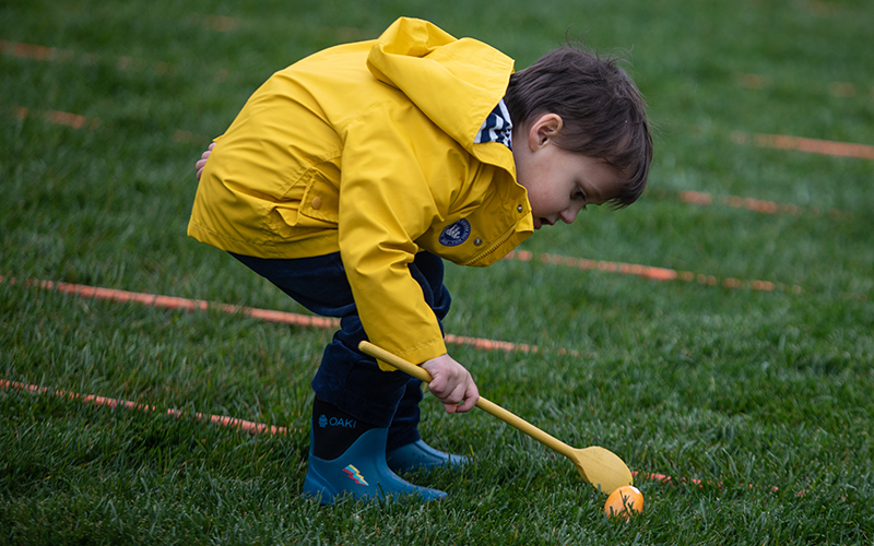 A child rolls an orange easter egg