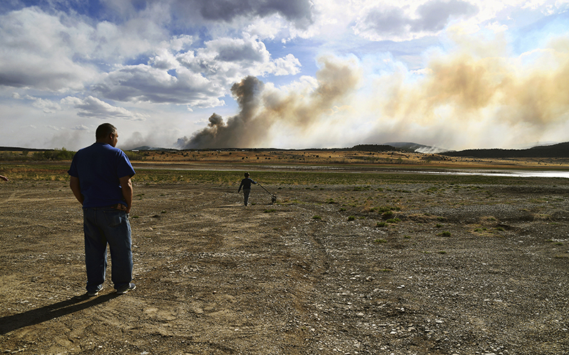 Leonard Padilla and 5-year-old Ivan Padilla watch a wildfire burn in the distance