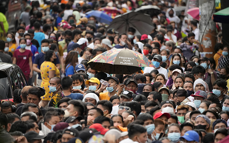 Crowds wait in line to vote at a polling station as one person holds an umbrella reading "Protect our planet" in the Tondo district of Manila, Philippines