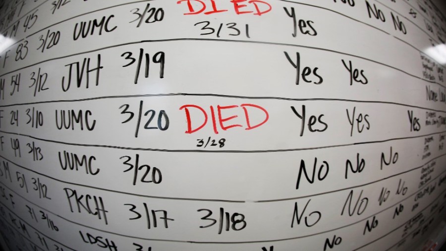 A hospital whiteboard notes COVID deaths in red marker..