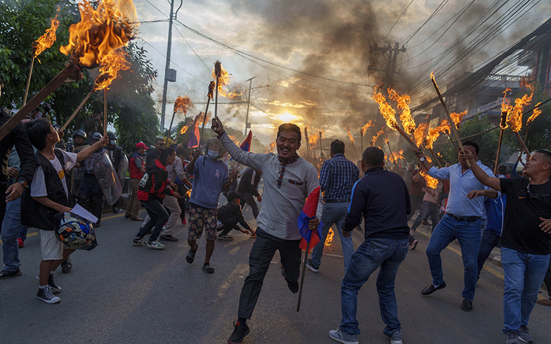 Nepalese student activists participate in a torch rally as a person in the center holds a flag