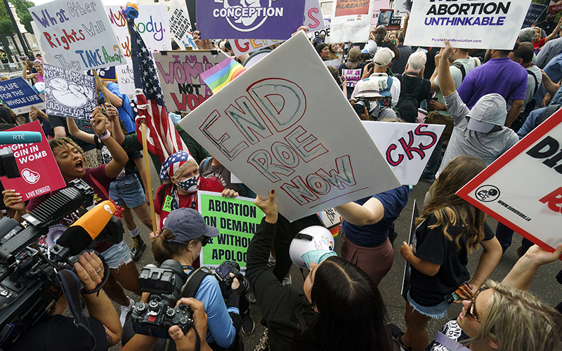 Protesters for and against abortion rights demonstrate outside the Supreme Court with signs, one of which reads "End Roe Now"