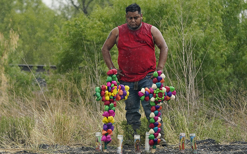 Rain falls as a man pays his respects at a memorial site