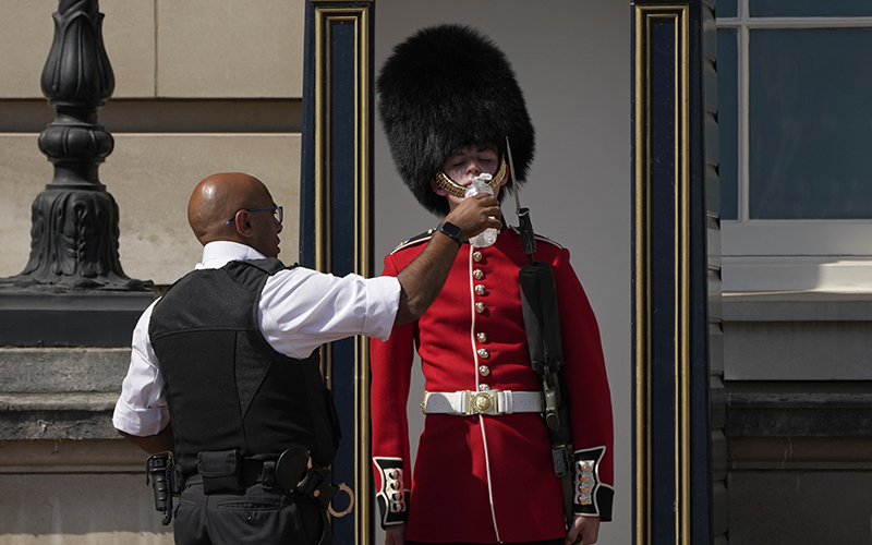 A police officer gives water to a British soldier