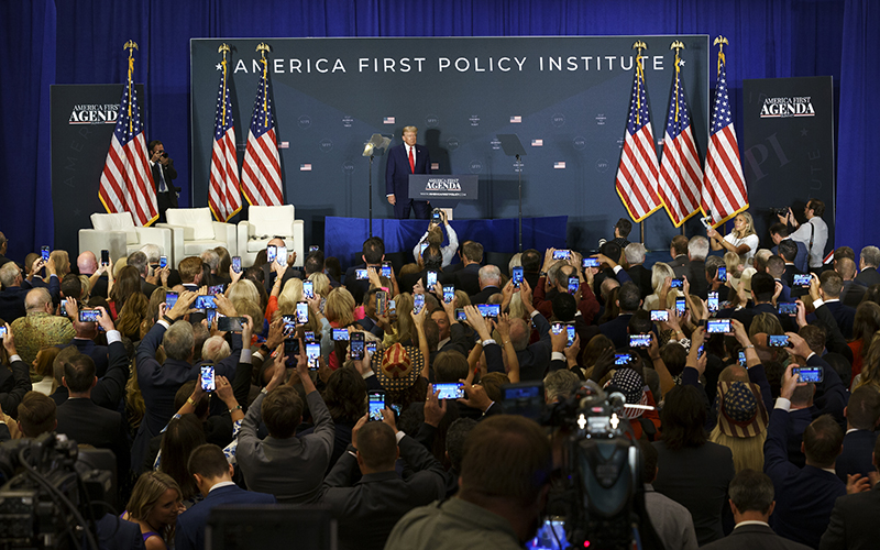 Former President Trump poses for photos on stage