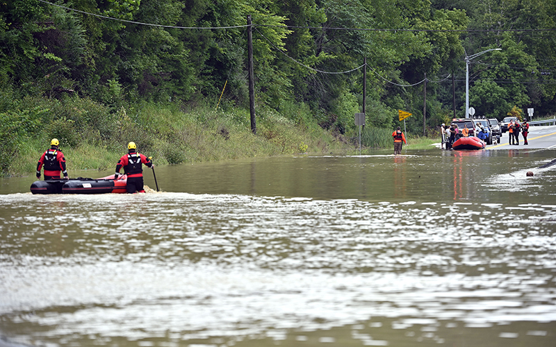 Rescue teams walk inflatable boats across flood waters