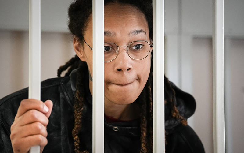 Brittney Griner speaks to her lawyers standing in a cage