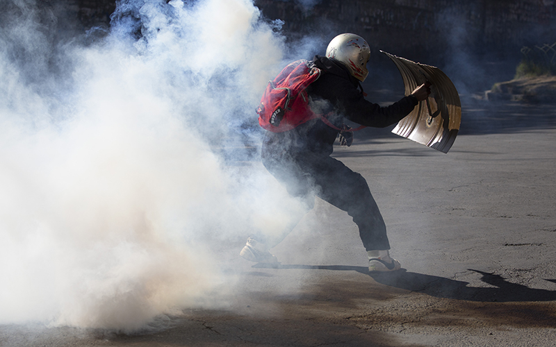 A coca farmer runs through a tear gas cloud