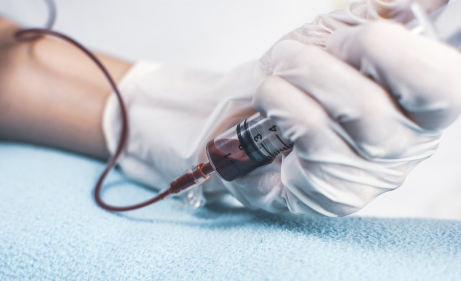 hand holding syringe taking blood sample