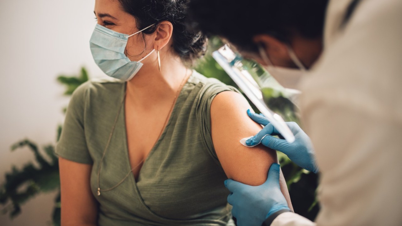 woman wearing a face mask getting a shot in her left arm